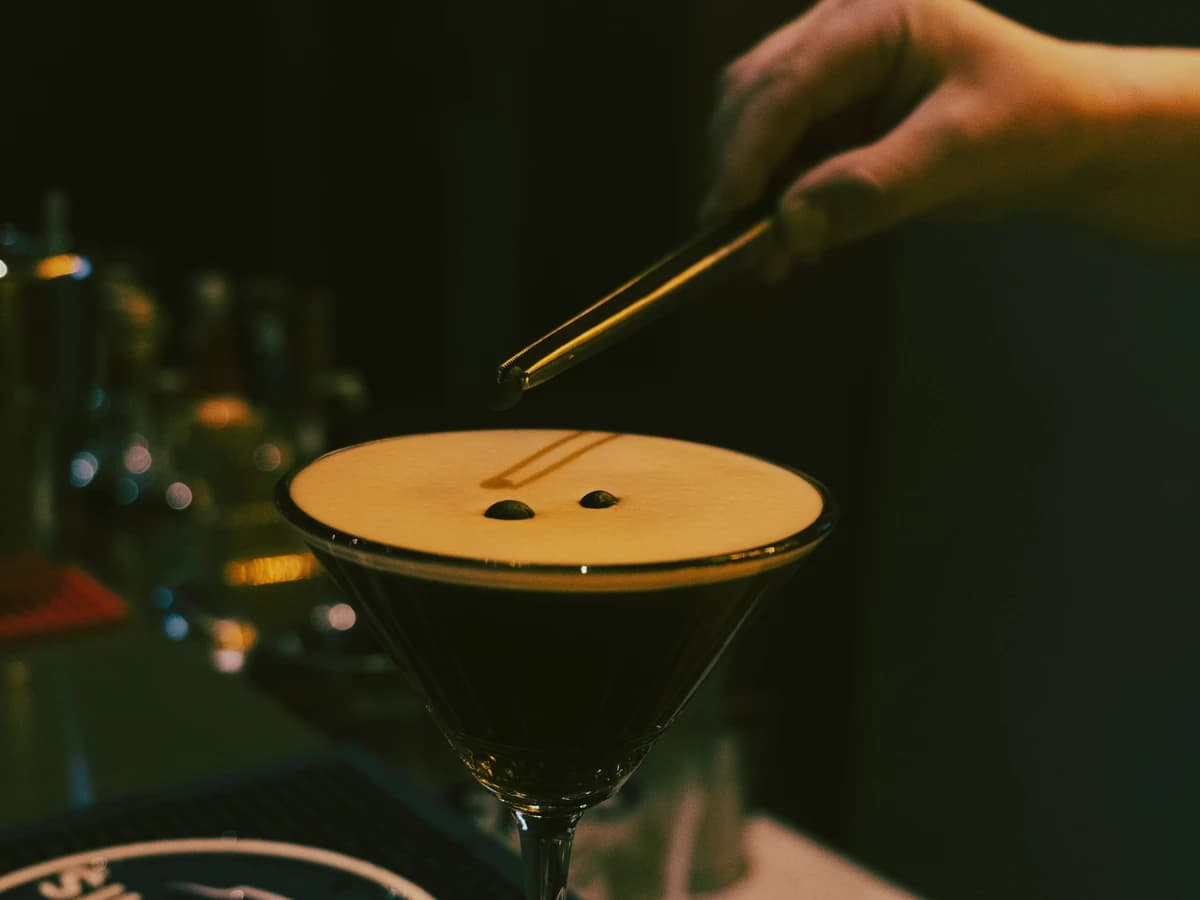 An Alcohol-Free Espresso Martini in a coupe glass with a thick coffee foam and three coffee beans