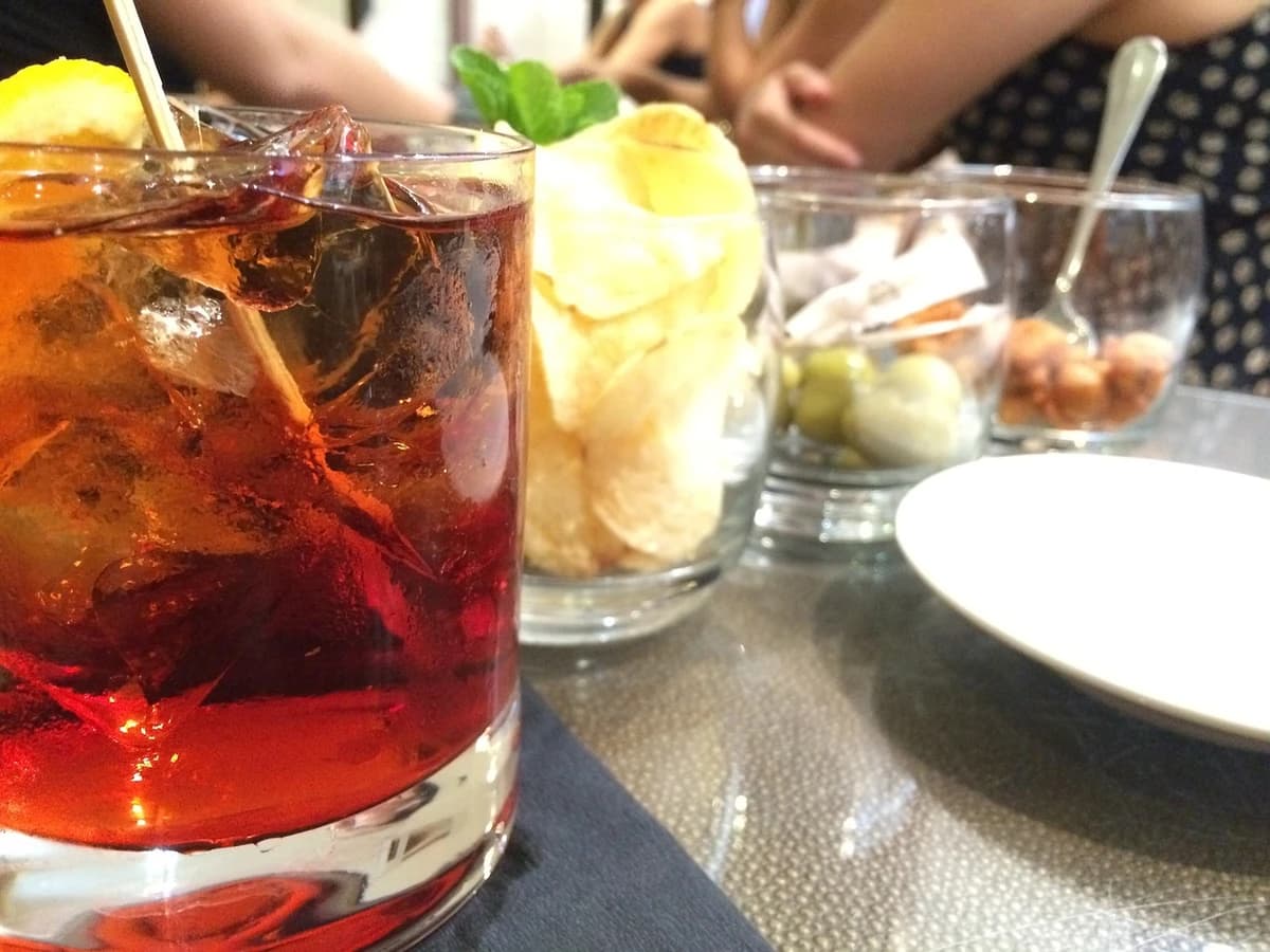 An alcohol-free Negroni in a rocks glass with a large ice cube and orange peel