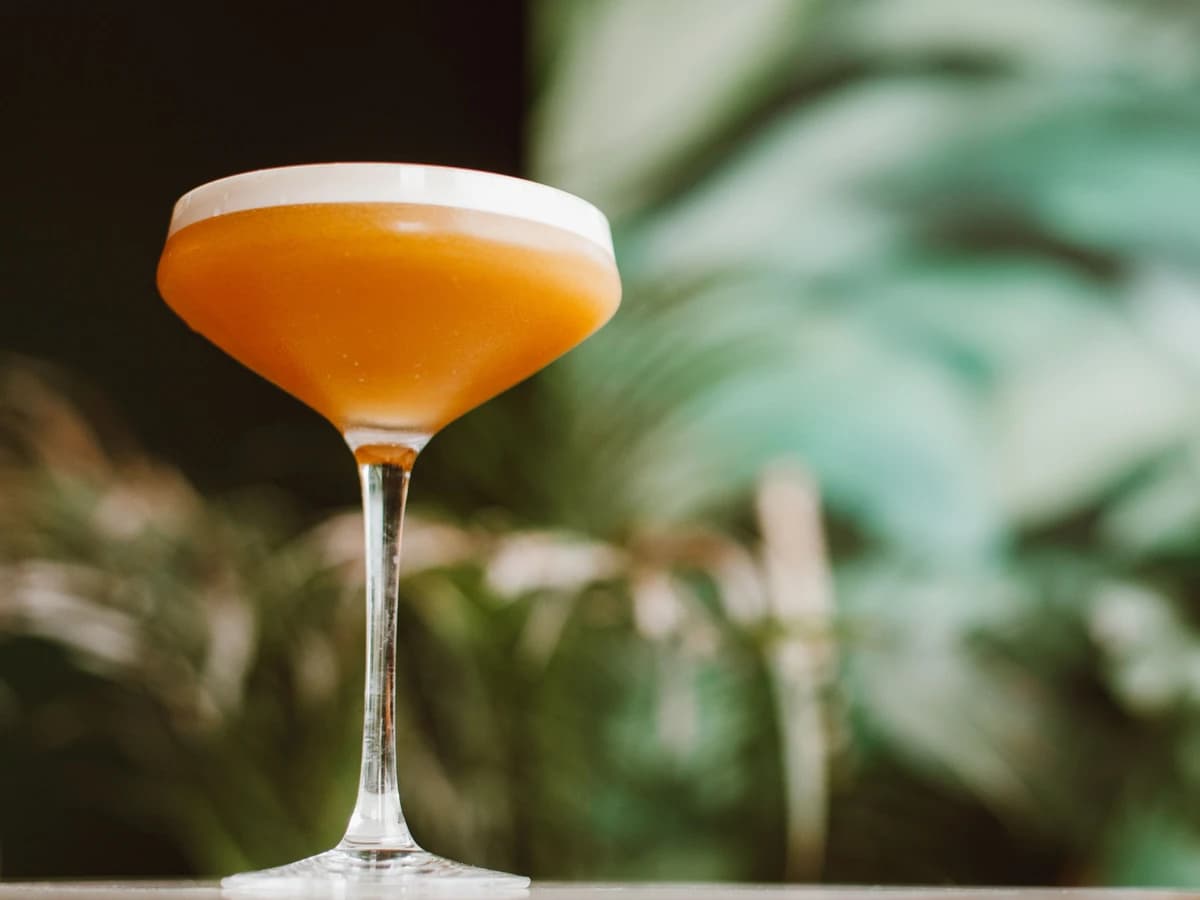 An Amaretto Sour in a rocks glass with a frothy top and a cherry garnish