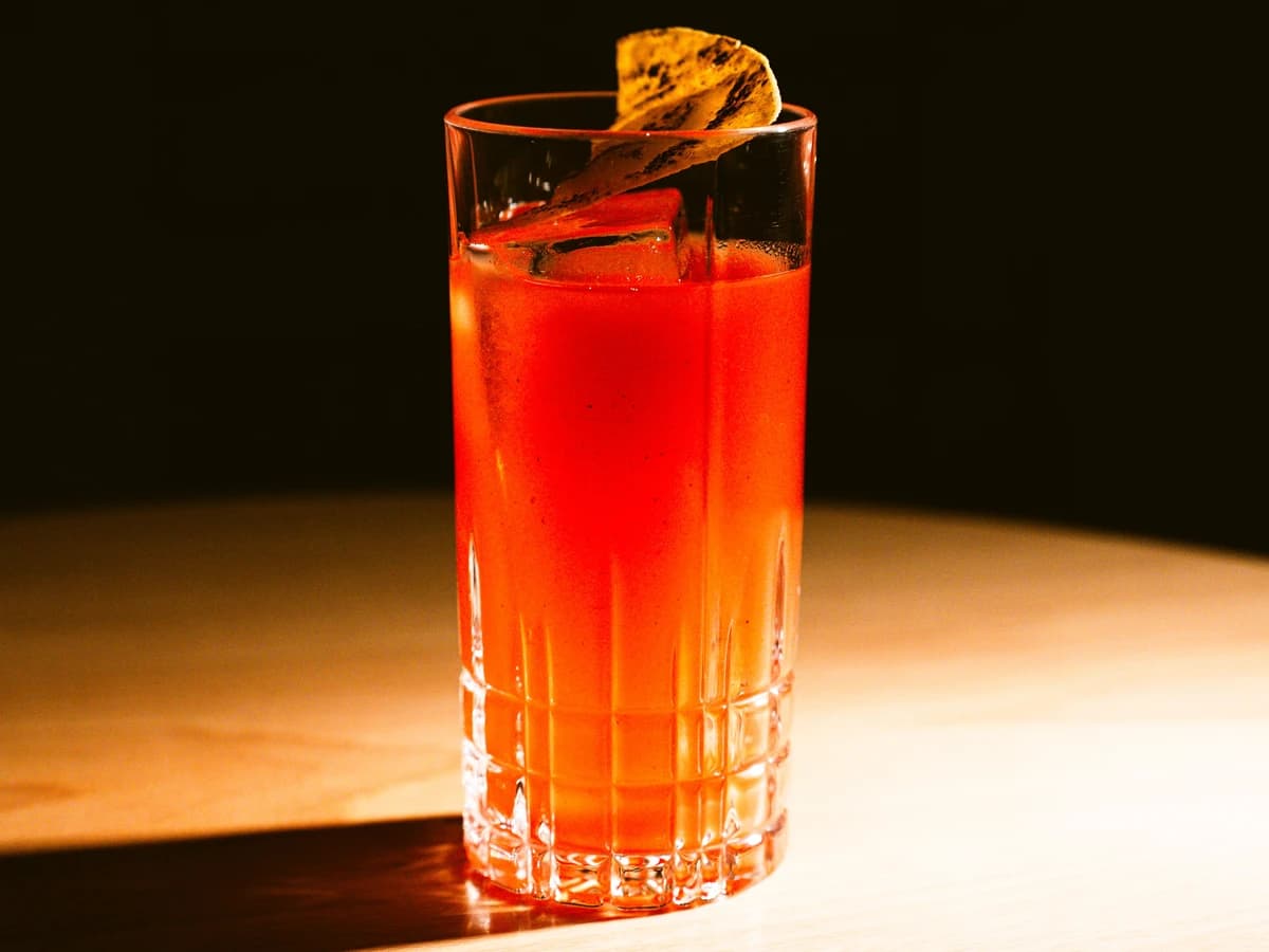 An Americano in a highball glass with an orange slice