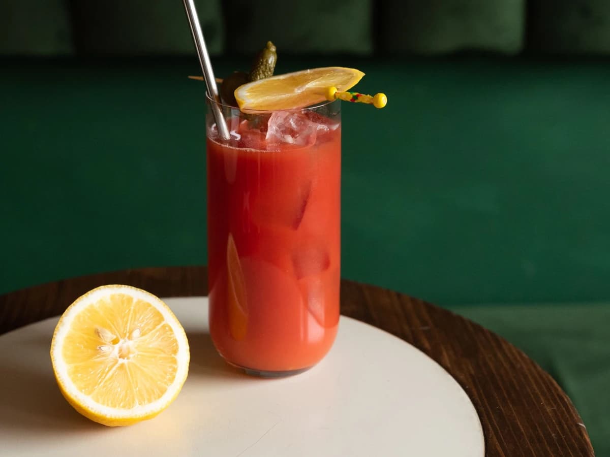 A Bloody Shame in a highball glass garnished with a celery stalk and lemon wedge