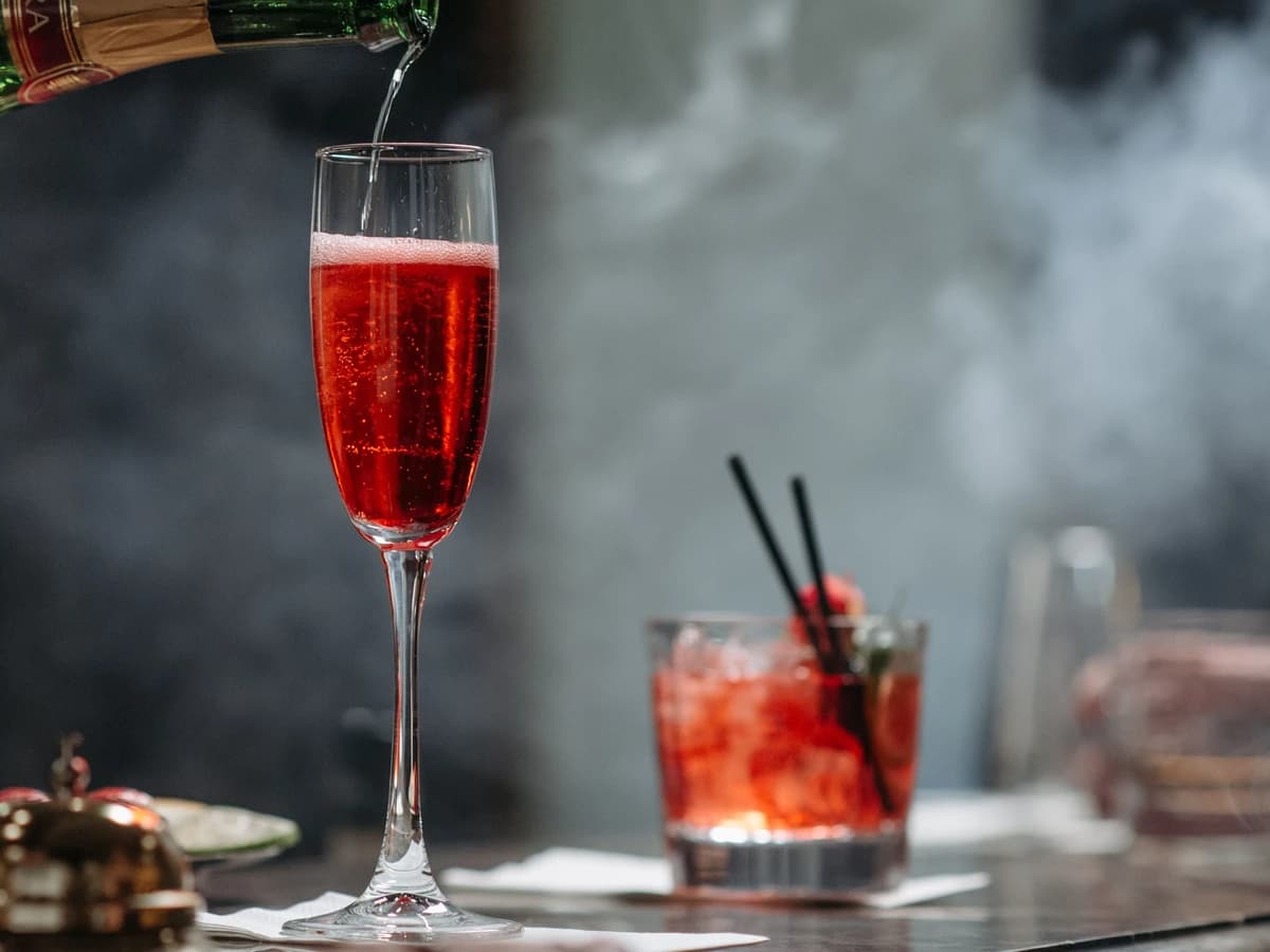 A punch bowl of Champagne Punch with an ice ring, alongside a filled champagne flute