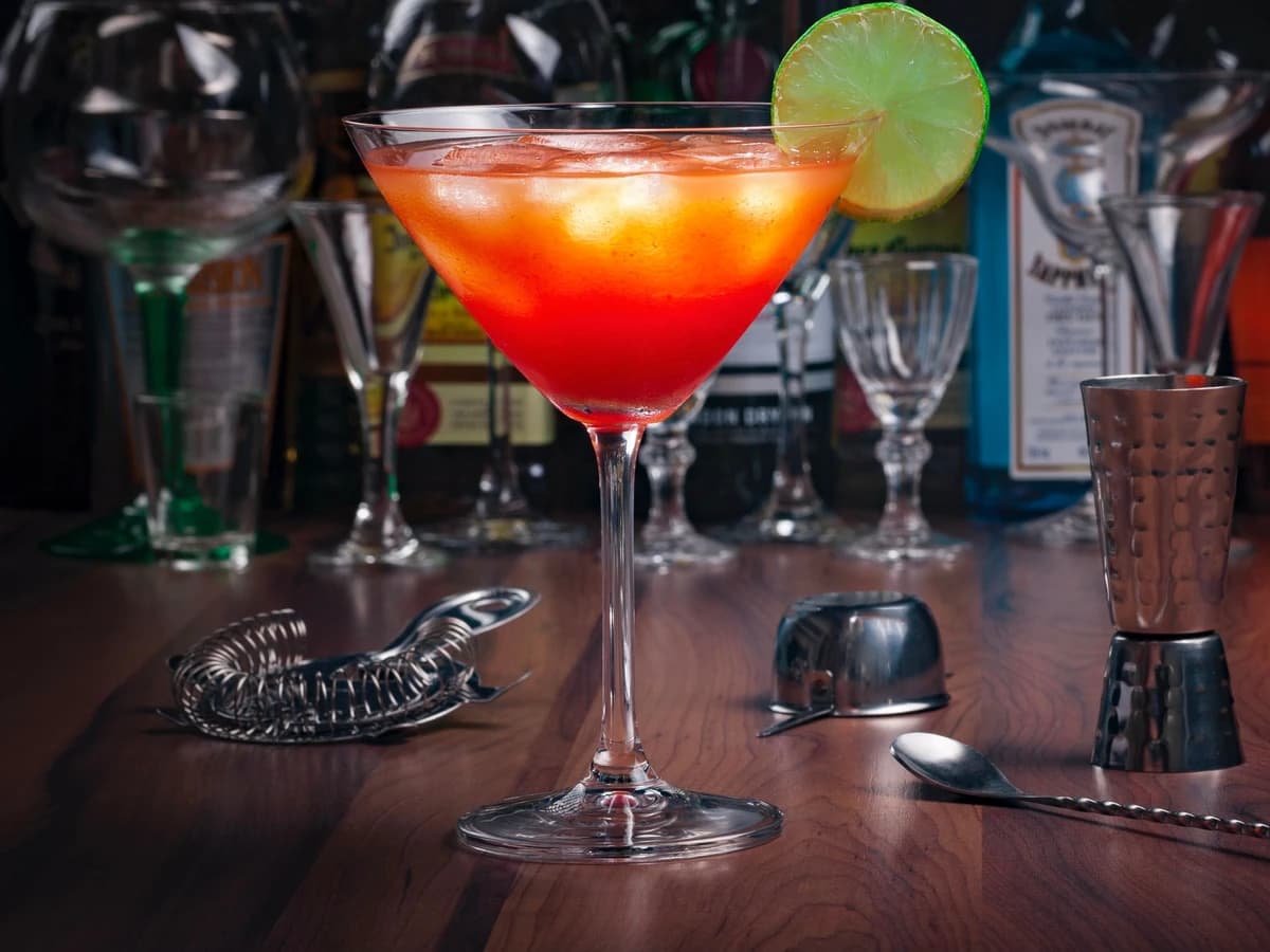 A pink Cosmopolitan in a coupe glass with an orange peel garnish