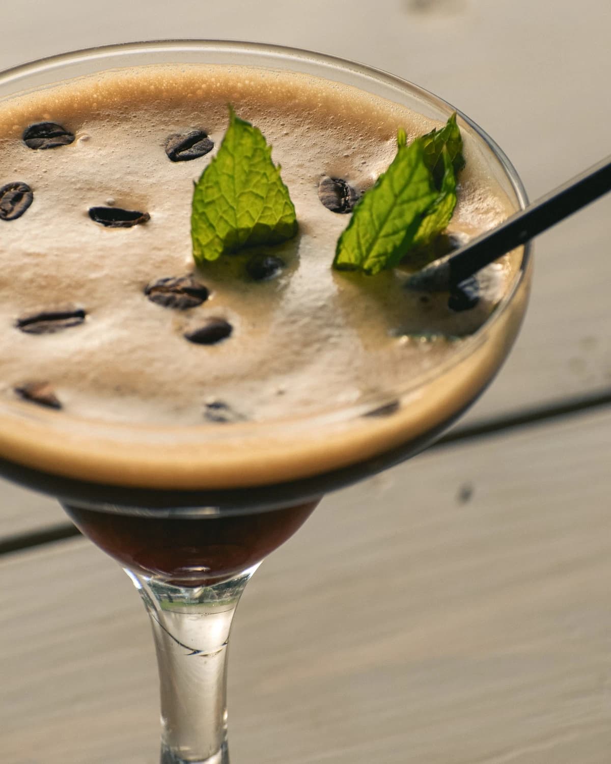 An Espresso Martini in a coupe glass with three coffee beans floating on the foam