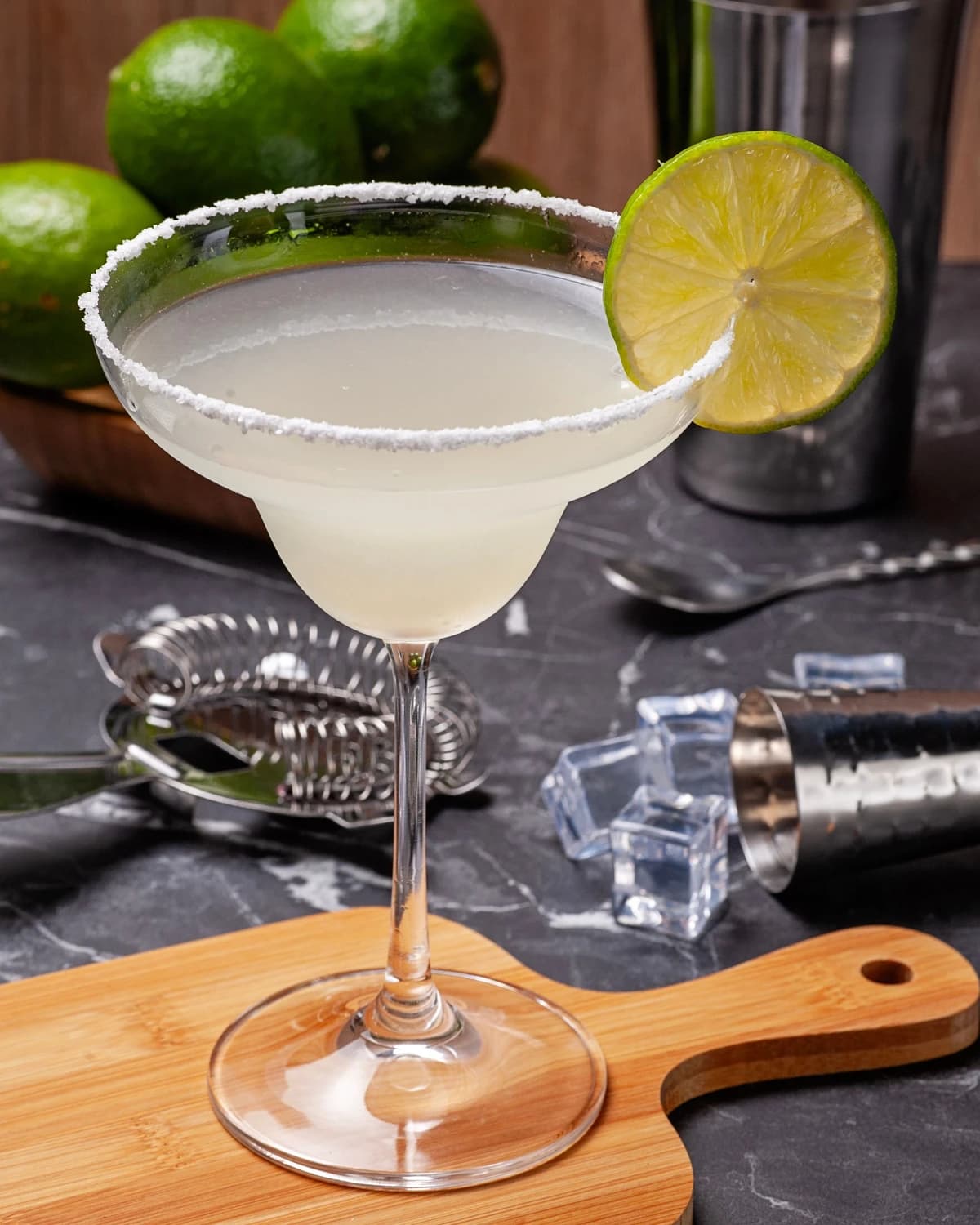 A salt-rimmed Margarita in a rocks glass with a lime wheel