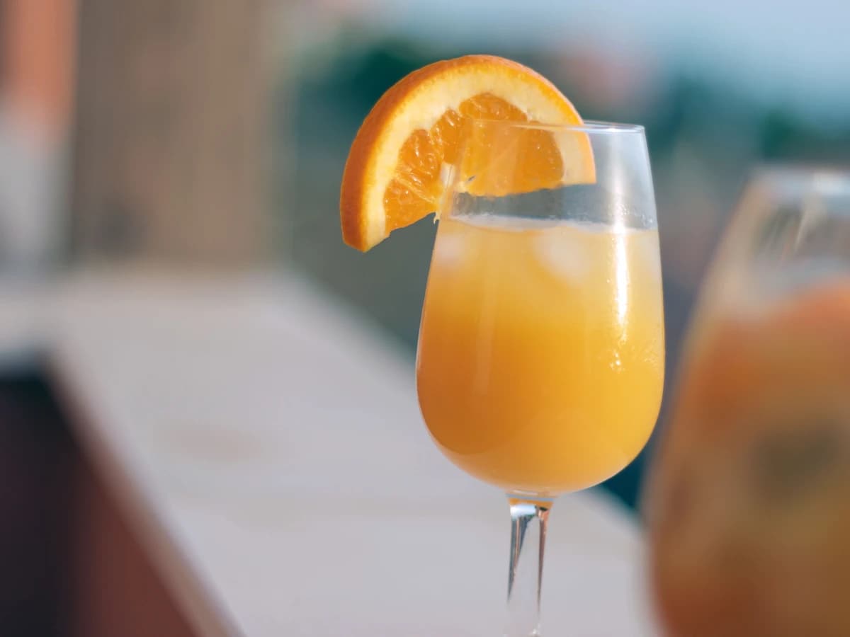 A Mimosa in a champagne flute, pale orange and fizzing