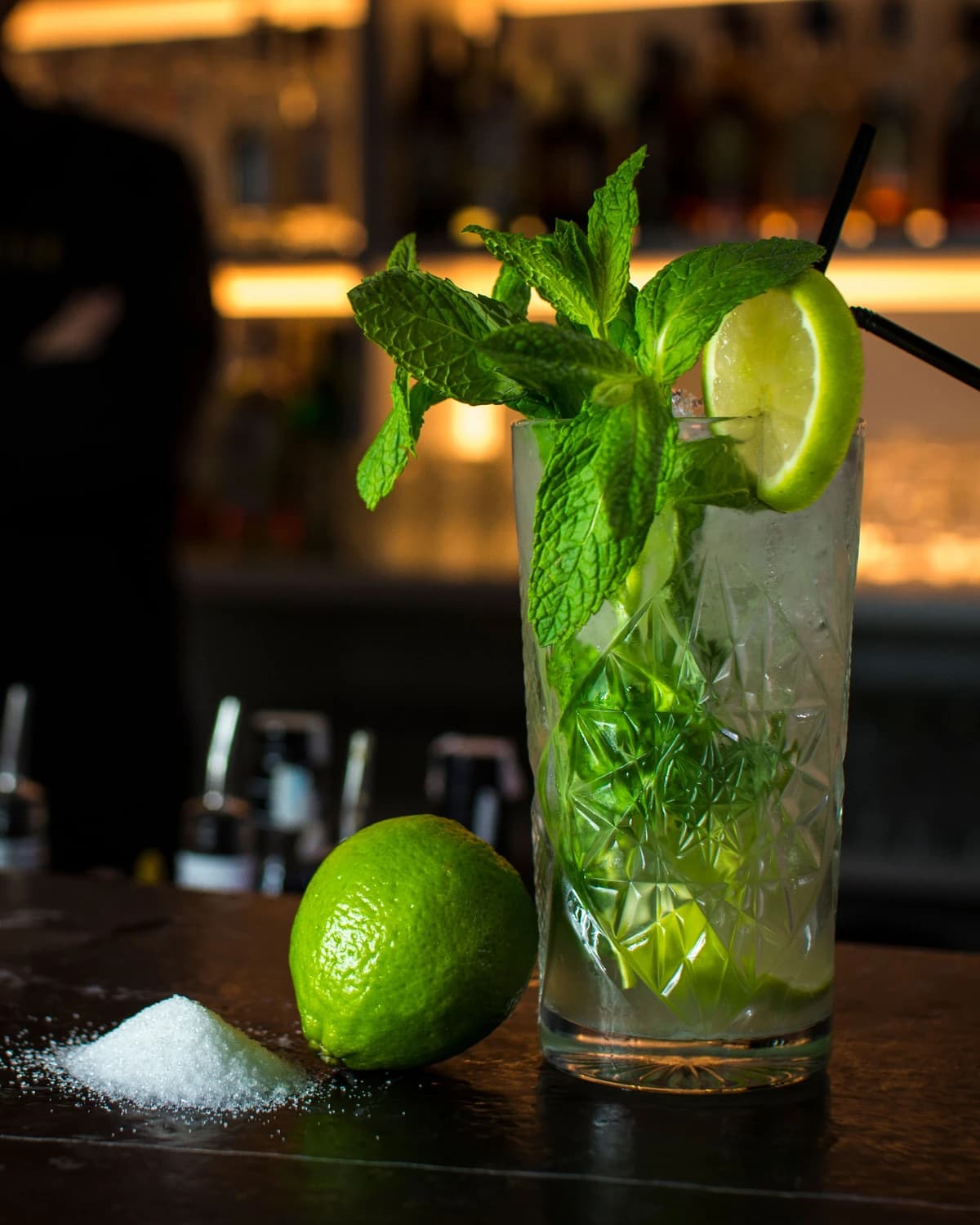 A tall mojito in a highball glass with mint sprig and lime wheel