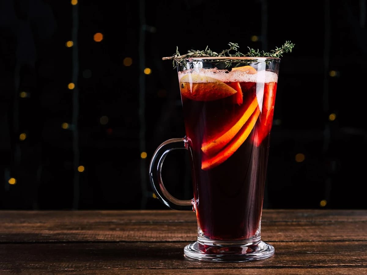 A mug of mulled wine with an orange slice, cinnamon stick and cloves