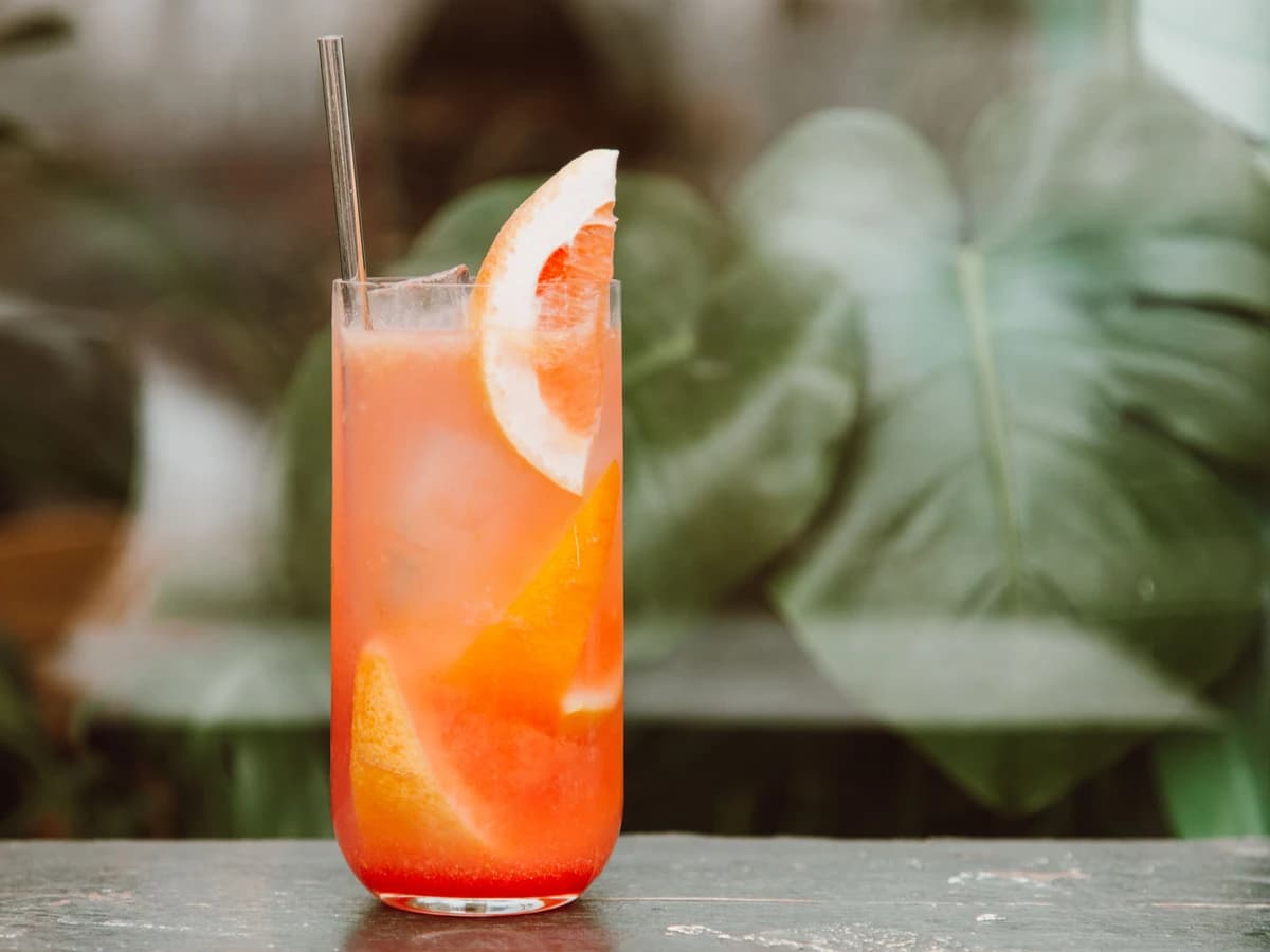 A Paloma in a highball glass with a grapefruit wedge and salted rim