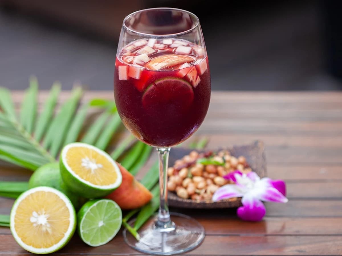 A pitcher of Sangria with orange and lemon slices, alongside a filled wine glass