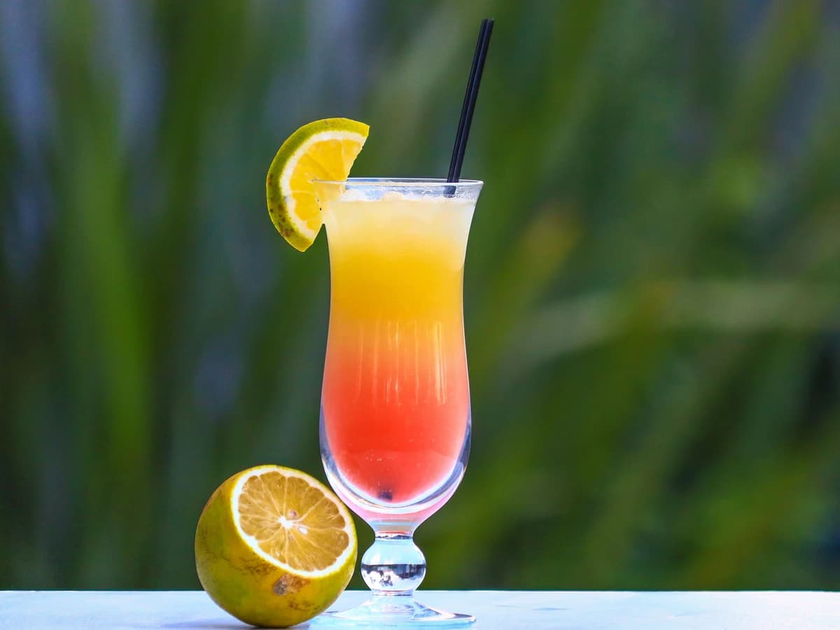 A Tequila Sunrise highball showing a red-to-orange gradient with grenadine settling at the bottom
