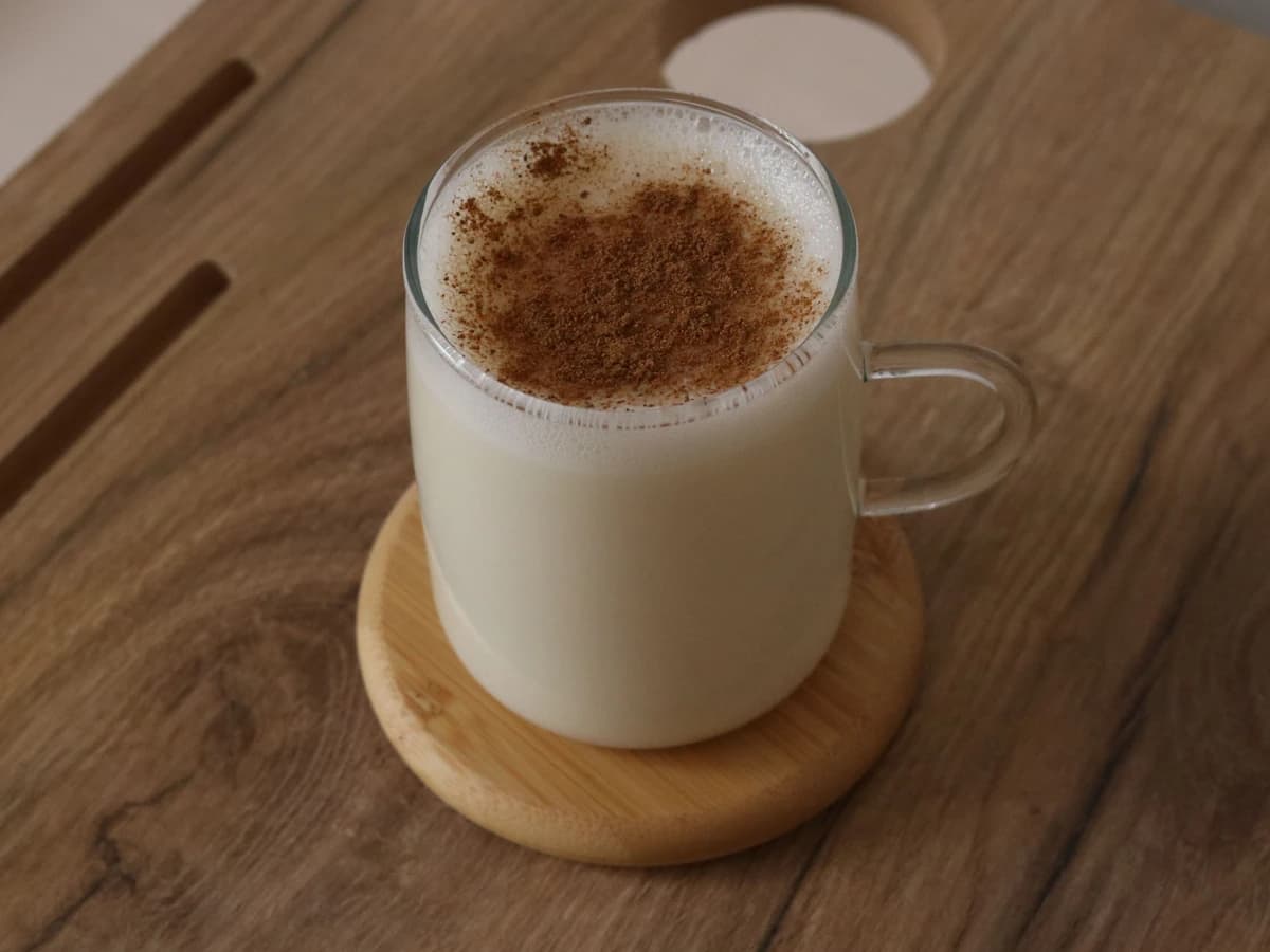 A Tom and Jerry in a heatproof punch mug with a frothy pale batter top and a dusting of nutmeg