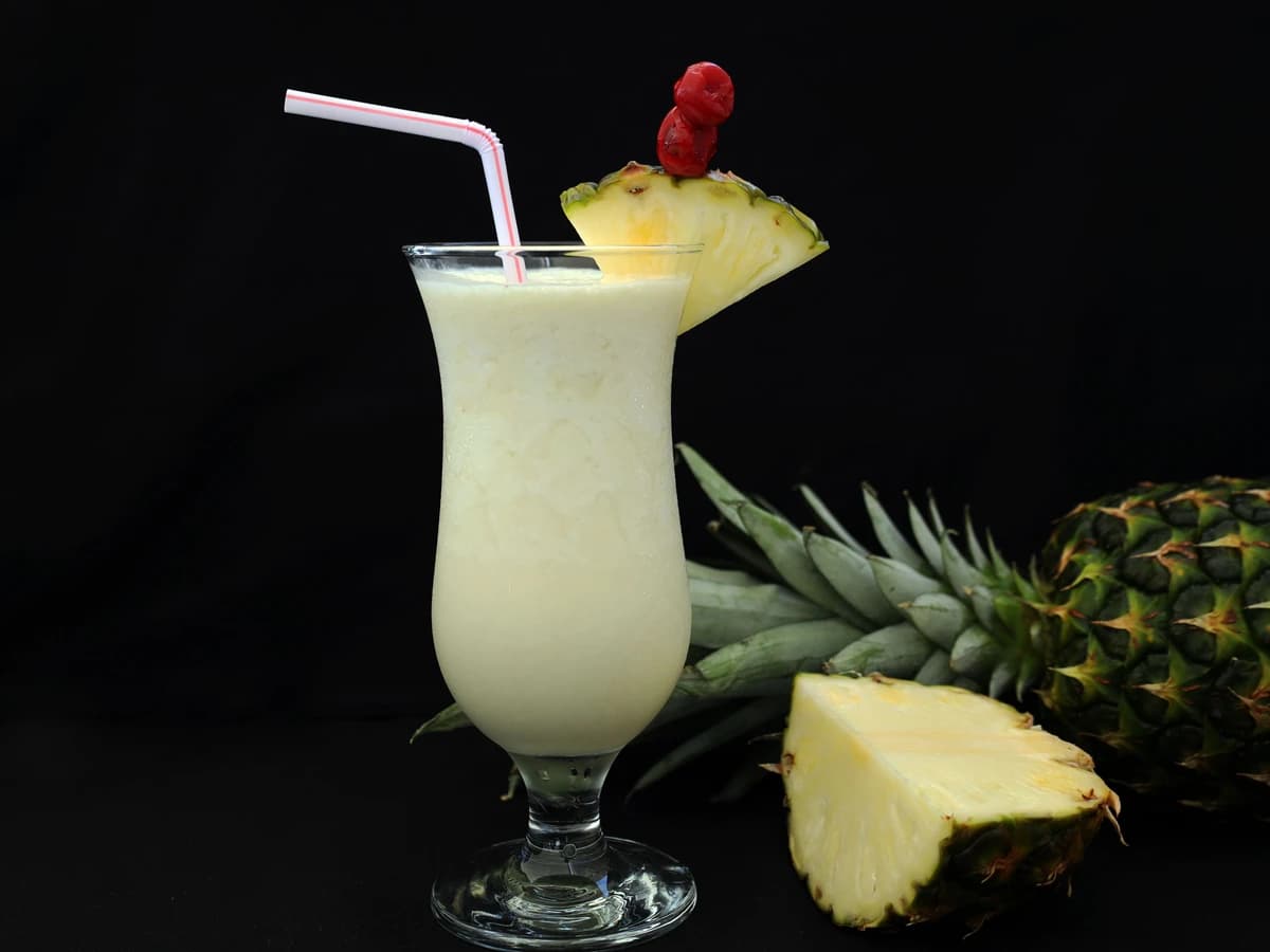 A blended virgin piña colada in a hurricane glass with a pineapple wedge and cherry