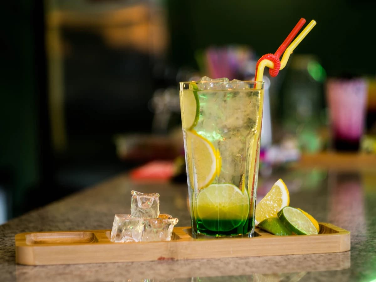 A tall Whisky Highball in a highball glass with a lemon twist and large ice cubes