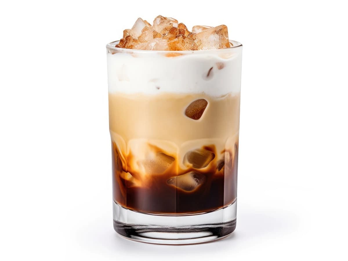A White Russian in a rocks glass with a cream layer on top of dark coffee liqueur